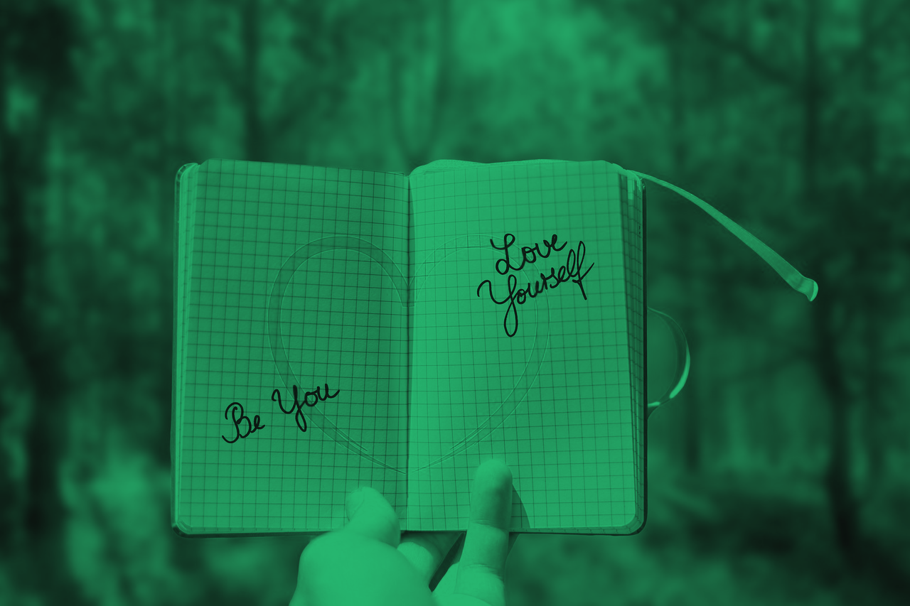  a notebook with a a red heart infornt of a scenary green forest